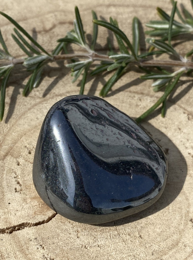 Glänzender Hämatit Trommelstein auf Holz