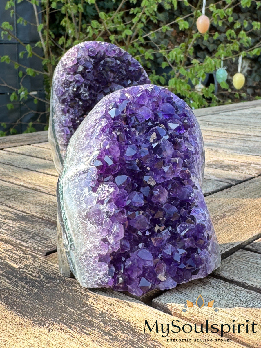 Eine Amethyst Druse ca. 10 cm hoch auf einem Holztisch.