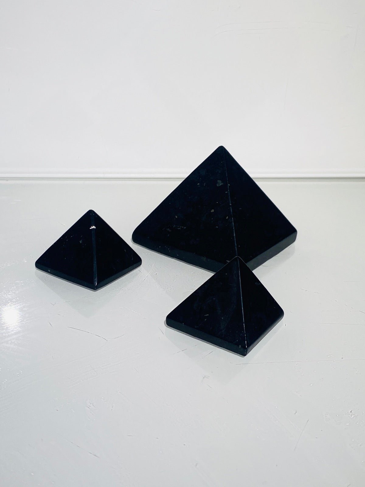 3 Stück schwarze Schungit Pyramiden in 3 - 5 cm auf weißem Hintergrund
